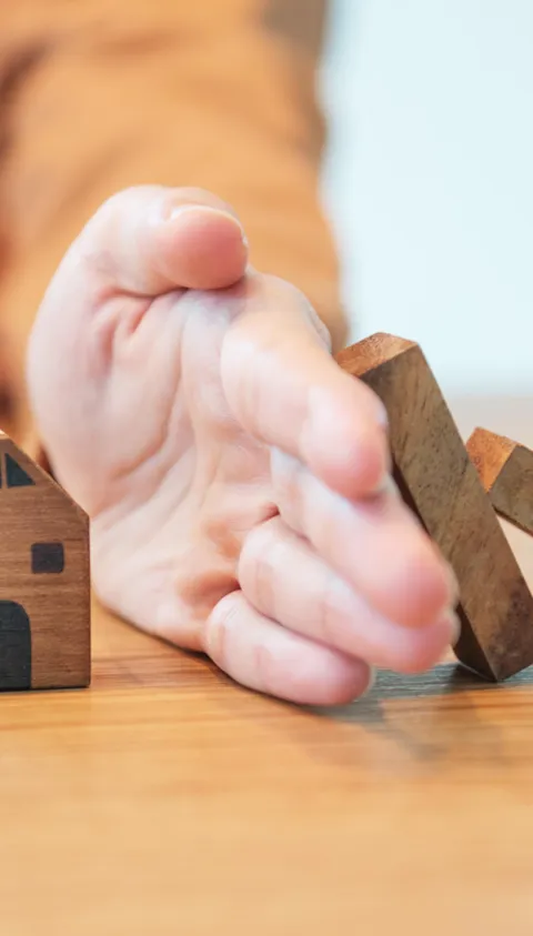 hand protecting house from brick fall